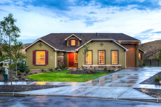Ranch-style house with lights on at dusk after rain