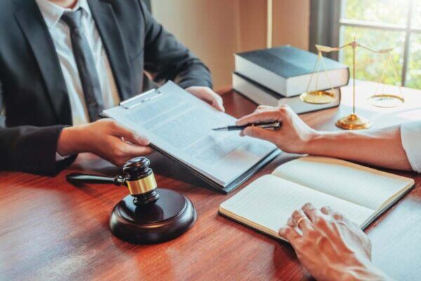 Gavel on a desk beside a person reviewing documents with a laptop and books