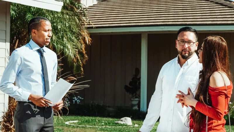 Agent and a couple talking on a patio outside a house