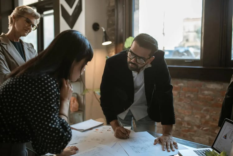 Group reviewing building plans spread across a table