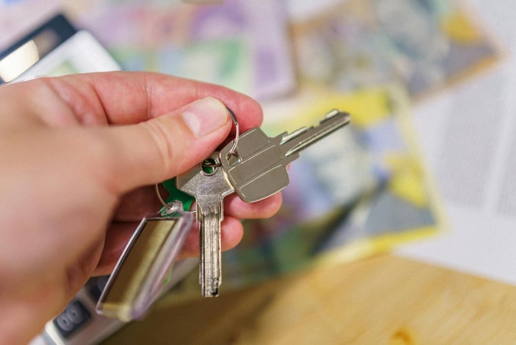 Hand holding a set of keys with blurred cash in the background